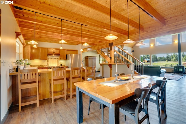 dining room featuring wood ceiling, light hardwood / wood-style floors, and beamed ceiling