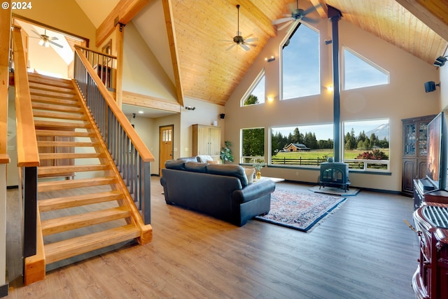 living room featuring a wealth of natural light, hardwood / wood-style floors, a wood stove, and high vaulted ceiling