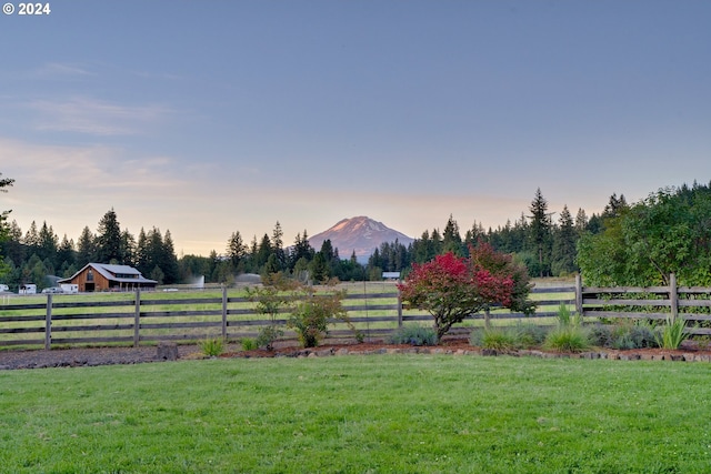 yard at dusk featuring a rural view and a mountain view