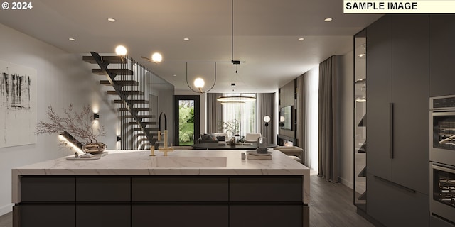 kitchen with dark wood-type flooring, light stone counters, pendant lighting, gray cabinets, and sink