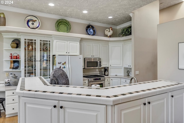 kitchen featuring tile countertops, white cabinets, and appliances with stainless steel finishes