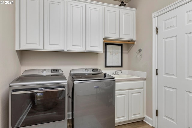 laundry room featuring cabinets, dark hardwood / wood-style floors, sink, and washing machine and clothes dryer