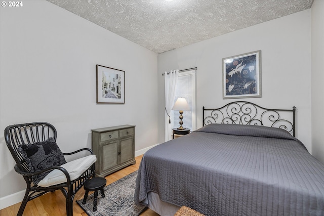 bedroom with a textured ceiling and light hardwood / wood-style floors