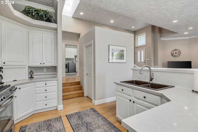 kitchen featuring a textured ceiling, light hardwood / wood-style floors, sink, and white cabinets