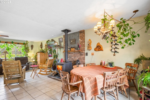 dining area featuring a wood stove, light tile patterned flooring, and ceiling fan with notable chandelier