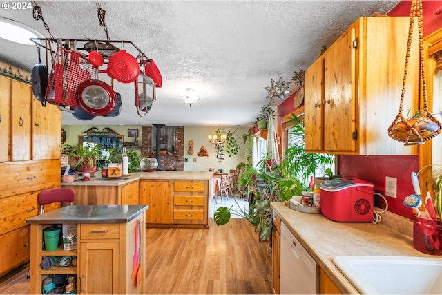 kitchen featuring light hardwood / wood-style floors, sink, white dishwasher, a textured ceiling, and an inviting chandelier