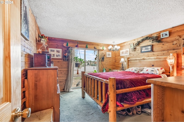 bedroom featuring a textured ceiling, access to outside, wooden walls, and light carpet