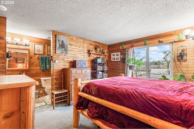 carpeted bedroom with wood walls and a textured ceiling