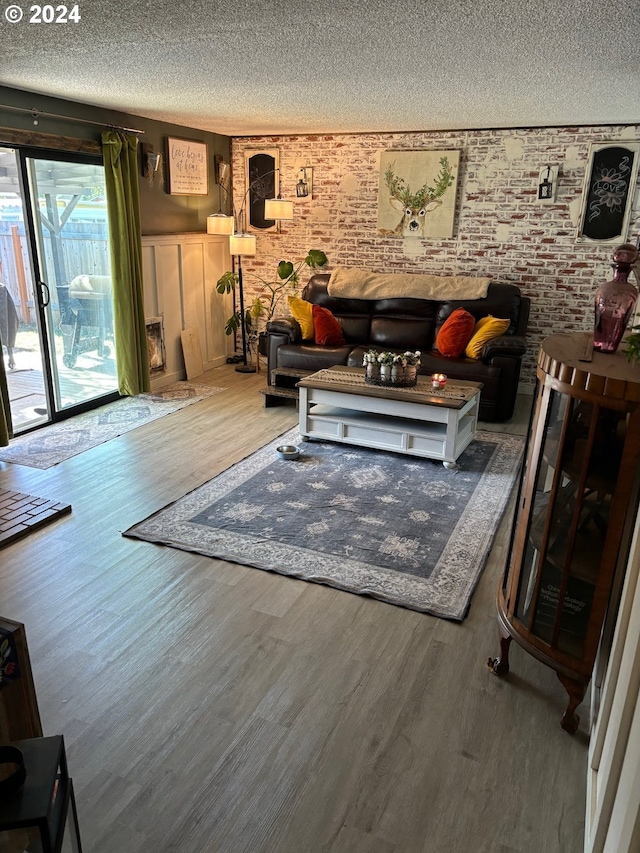 living room with hardwood / wood-style flooring, a textured ceiling, and brick wall