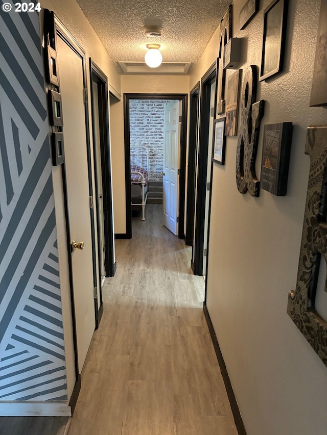 hallway with a textured ceiling and light wood-type flooring