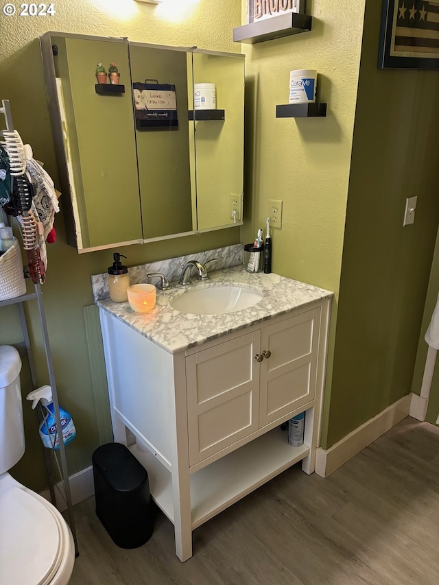 bathroom with hardwood / wood-style flooring, vanity, and toilet