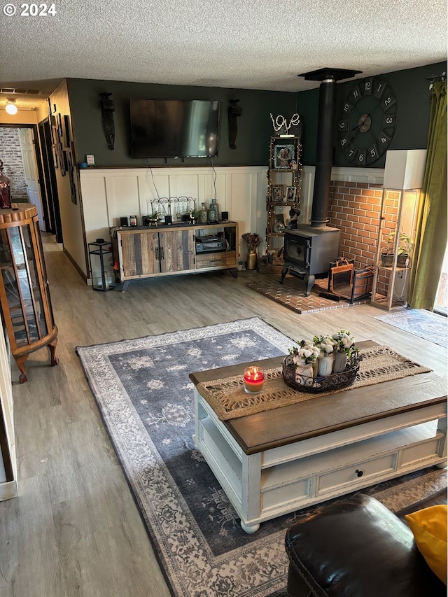 living room featuring a textured ceiling, light hardwood / wood-style floors, and a wood stove