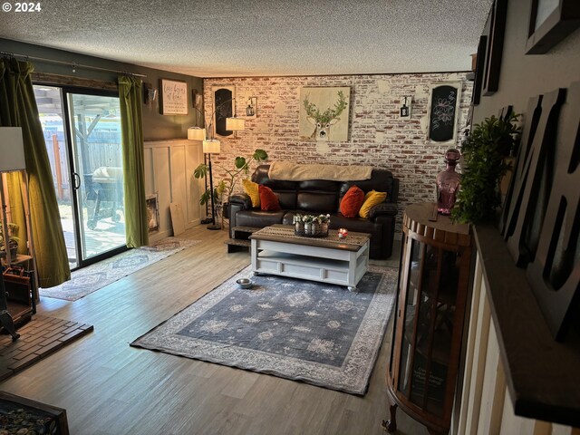 living room with a textured ceiling, light wood-type flooring, and brick wall