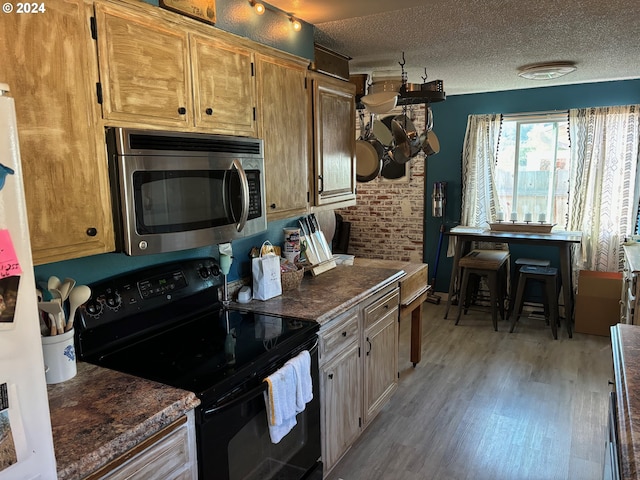 kitchen with a textured ceiling, light wood-type flooring, and black range with electric stovetop