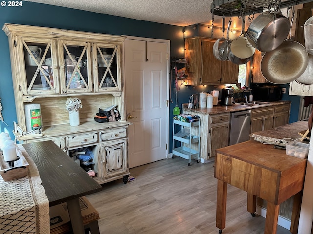 kitchen with dishwasher, light hardwood / wood-style floors, sink, and a textured ceiling