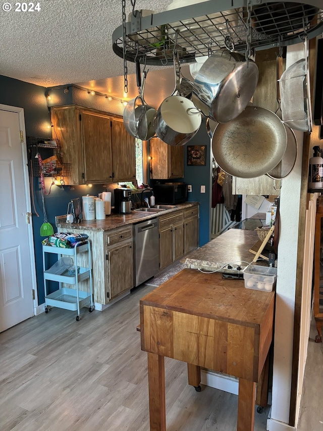 kitchen featuring stainless steel dishwasher, a textured ceiling, and light hardwood / wood-style floors