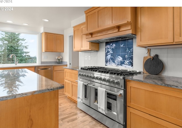 kitchen featuring stone countertops, backsplash, stainless steel appliances, sink, and light wood-type flooring