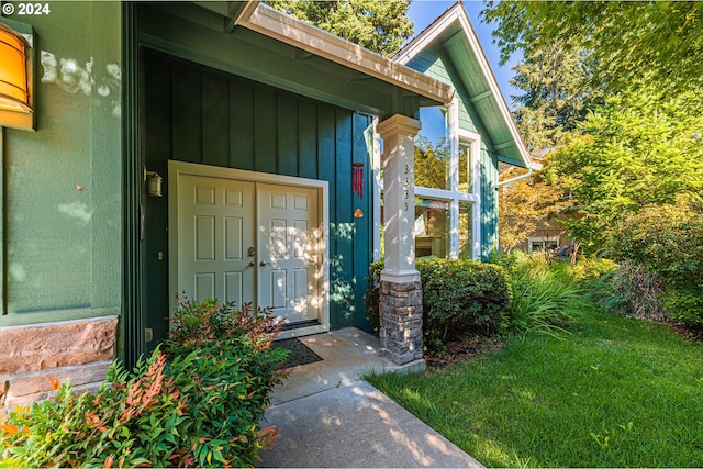 entrance to property featuring stone siding, board and batten siding, and a yard