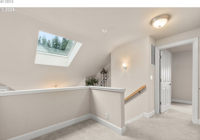 interior space featuring vaulted ceiling with skylight and carpet