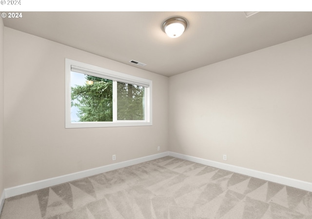 empty room featuring light colored carpet, visible vents, and baseboards