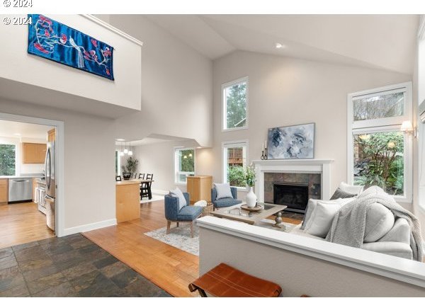 living room with high vaulted ceiling, hardwood / wood-style floors, and a tile fireplace