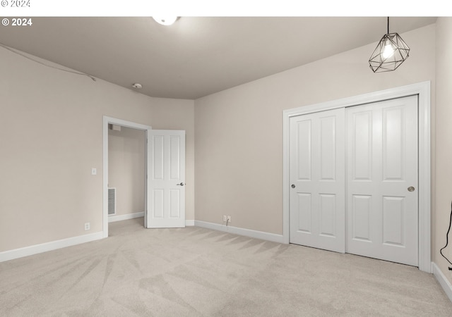 unfurnished bedroom with light carpet, baseboards, visible vents, and a closet