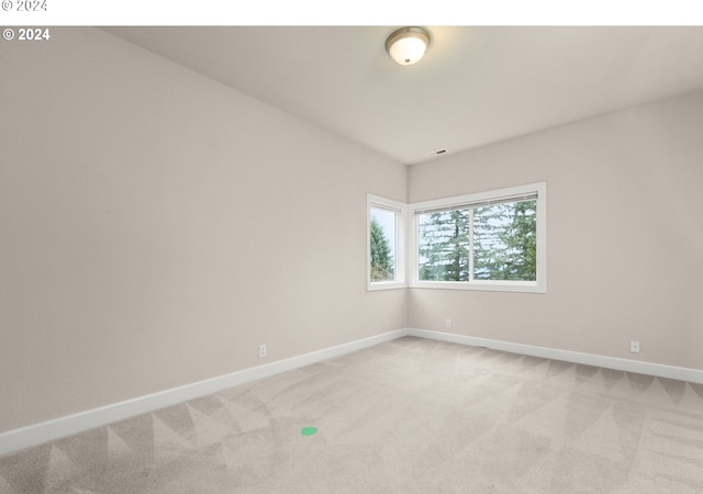 spare room with light carpet, visible vents, and baseboards