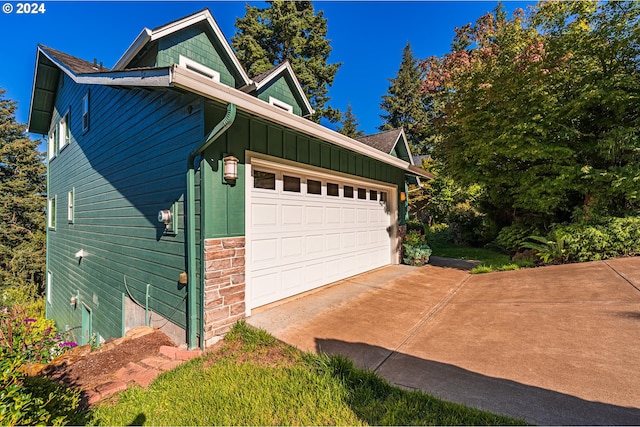 view of property exterior featuring stone siding, concrete driveway, board and batten siding, and an attached garage