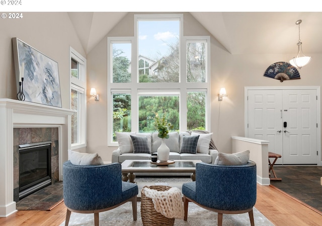 living room featuring high vaulted ceiling, light wood-type flooring, and a tiled fireplace