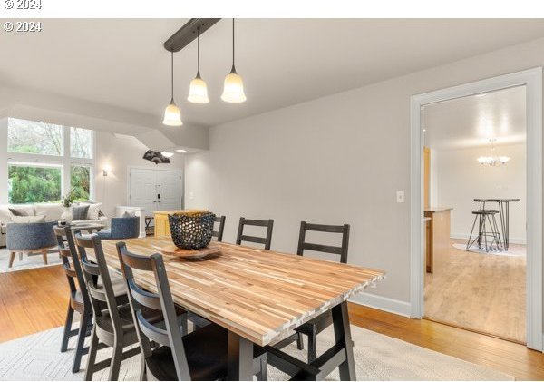 dining area with light wood-type flooring and a notable chandelier