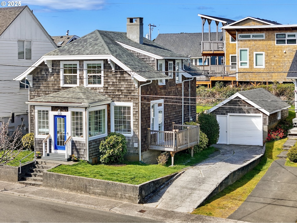 view of front of property with driveway, a chimney, an outbuilding, a shingled roof, and entry steps