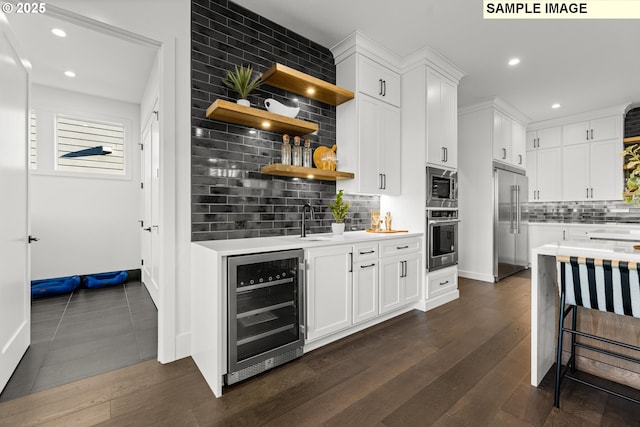 kitchen with sink, beverage cooler, decorative backsplash, white cabinets, and appliances with stainless steel finishes