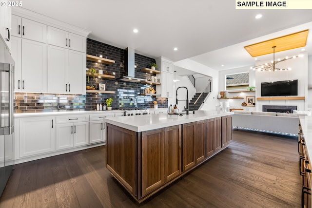 kitchen with a kitchen island with sink, sink, decorative backsplash, dark hardwood / wood-style flooring, and white cabinetry