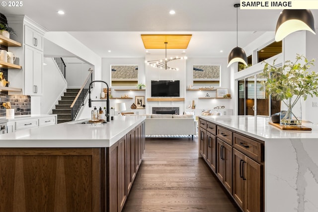 kitchen featuring a center island with sink, decorative backsplash, decorative light fixtures, dark hardwood / wood-style flooring, and white cabinetry