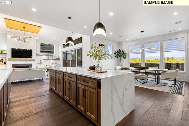 kitchen with a healthy amount of sunlight, light stone countertops, pendant lighting, and dark hardwood / wood-style floors