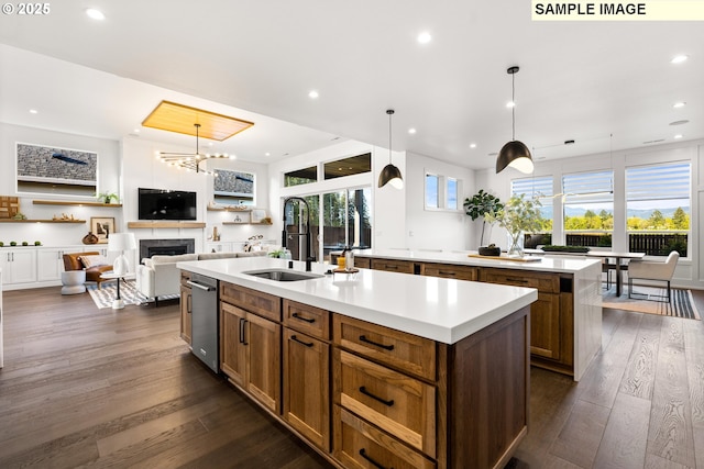 kitchen featuring decorative light fixtures, a kitchen island with sink, dark wood-type flooring, and sink