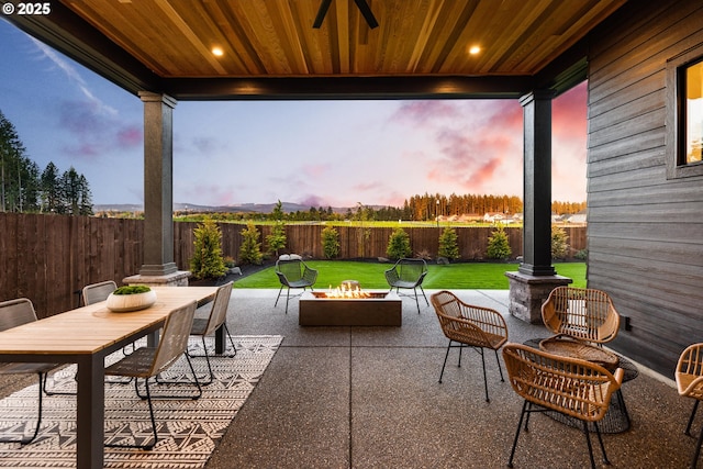 patio terrace at dusk with an outdoor living space with a fire pit and a lawn