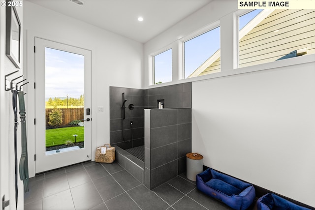 bathroom with a tile shower and tile patterned flooring