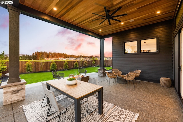 patio terrace at dusk featuring ceiling fan and a lawn