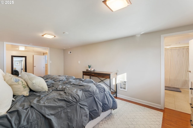 bedroom featuring ensuite bathroom and light wood-type flooring