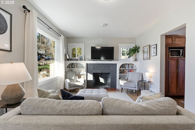 living room featuring wood-type flooring and a brick fireplace