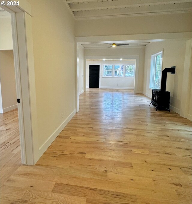 unfurnished living room with a wood stove, ornamental molding, and light wood-type flooring