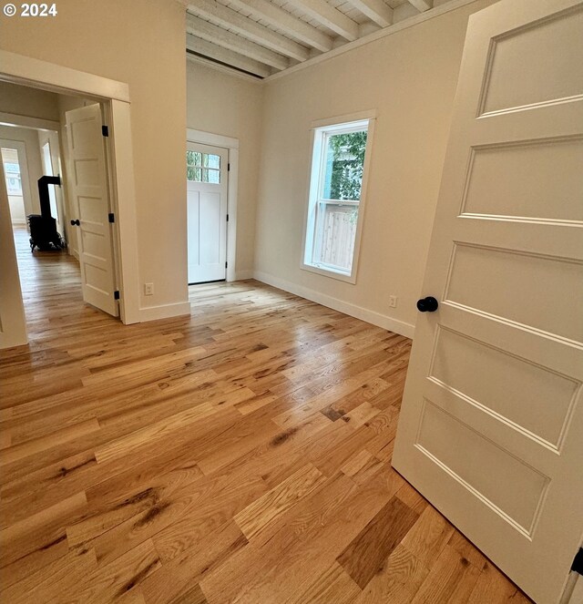 unfurnished room with beam ceiling and light hardwood / wood-style flooring