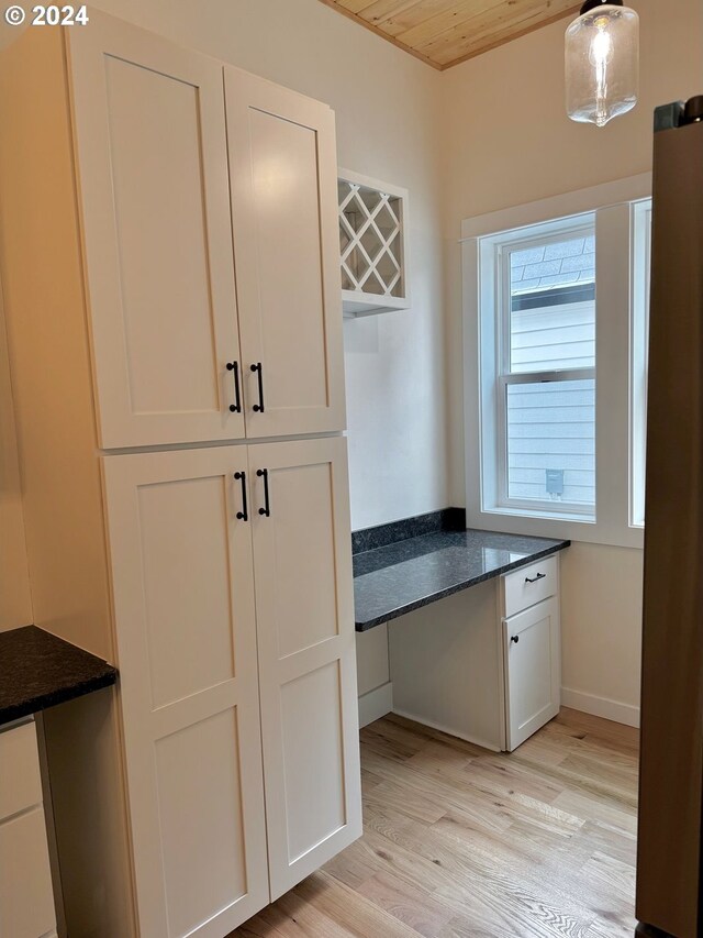 kitchen featuring wood ceiling, hanging light fixtures, white cabinetry, dark stone counters, and light hardwood / wood-style flooring