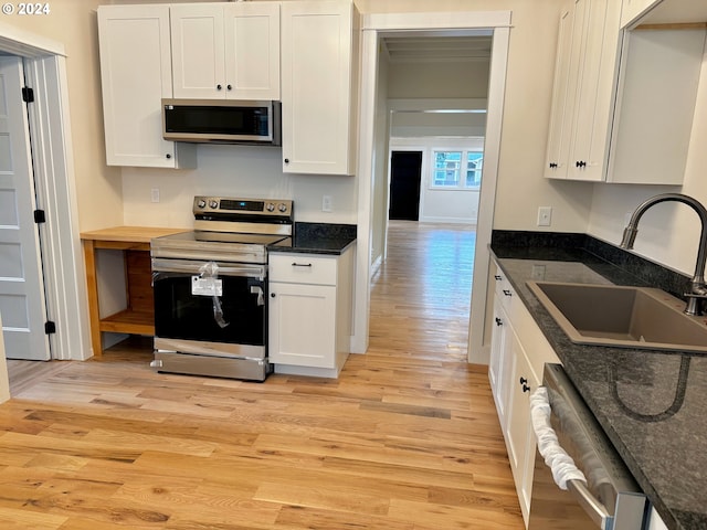 kitchen with sink, appliances with stainless steel finishes, white cabinets, and light hardwood / wood-style floors