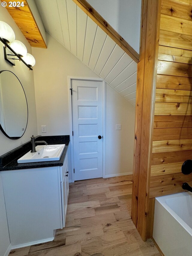 bathroom with vanity, lofted ceiling, a bathing tub, and wood-type flooring