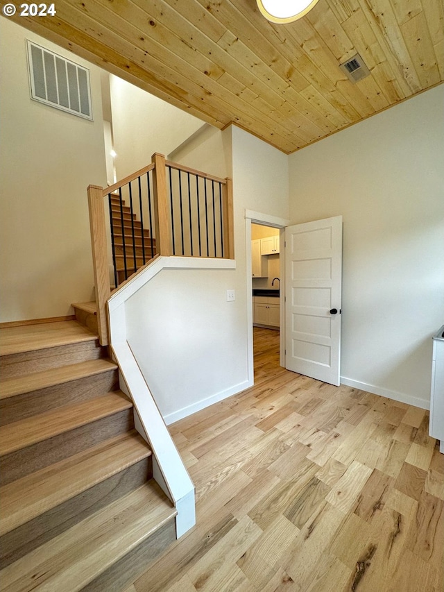 stairs with wooden ceiling, sink, and hardwood / wood-style floors