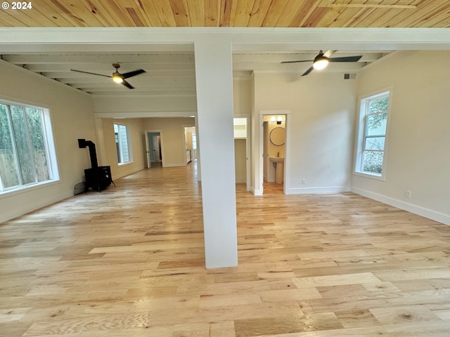 unfurnished living room featuring wood ceiling, a wood stove, beam ceiling, and light wood-type flooring