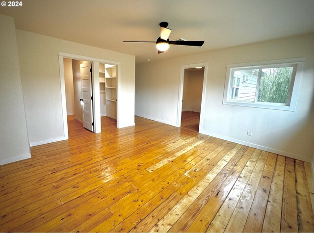 unfurnished bedroom with a spacious closet, light hardwood / wood-style floors, and ceiling fan