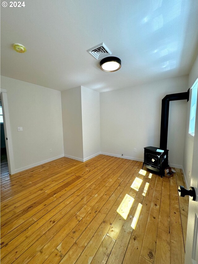 unfurnished living room with light wood-type flooring and a wood stove